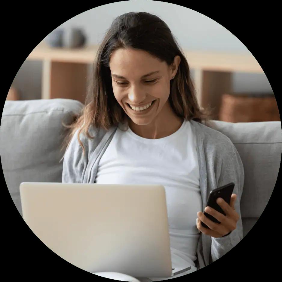 Woman sitting on a couch with a phone and laptop